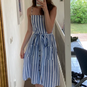 Klänning  - Blå och vit randig klänning som aldrig använts. Den har dragkedja på ena sidan och bältet går att justera!