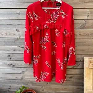 Supersöt röd blommig klänning med volang + en liten knytning i nacken, strl S 