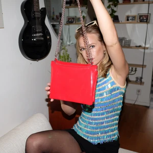 Röd väska från Monki - Äldre röd Monkiväska med kedjeliknande axelrem. Väskan säljs då knappen är sönder och jag är för ohändig för att laga.  Det är verkligen den perfekta lilla väskan. Avundsjuk på dess framtida ägare 💕