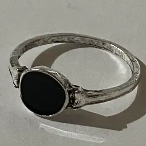 Silverring i form av en svart cirkel.