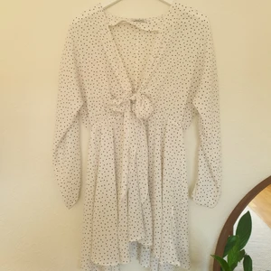 Klänning från Chiquelle stl M - Vit kortkänning med små svarta prickar och knytning framtill, från Chiquelle. Stl M. Endast använd en gång. Frakt tillkommer.