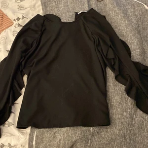 Svart blus - Svart blus med volanger från Gina tricot. Använd ett fåtal gånger men är som ny! Endast volanger på armarna. För liten i armarna för mig så det är därför den inte kommer till användning. Köparen står för frakt. Pris kan diskuteras 