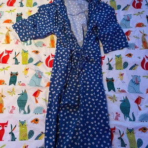 Blå långklänning - Säljer en blå långklänning med vita blommor och som man knyter runt magen, den är så så vacker 