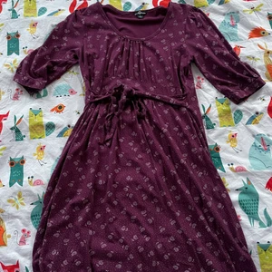 Lila tunika - Säljer en vinröd/lila tunika med vita blommor och som man knyter runt midjan. Det kanske är en klänning den går till runt knäna