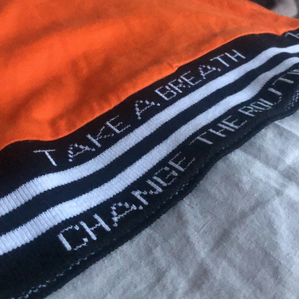 Orange tröja med textdetaljer i kanterna. Tröjan har andvänds 2-3 gånger. Den är köpt på en butik i Frankrike som heter Jennyfer.. T-shirts.