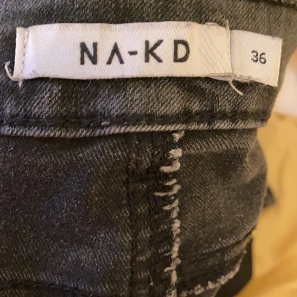Svart/gråa jeans från NAKD i strl 36 med slits nedtill . Jeans & Byxor.