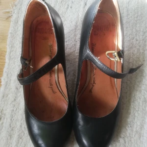 Roots,  skinnpumps - Svarta, snygga obetydligt använda skinnpums med rem över foten. 