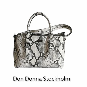 Don Donna Stockholm Väska.  - Väska i ormskinsmönster vegan 100% läder. Kan användas både med handtag och en axelrem. Fina detaljer. Rymlig med flera fack. Svart tyg foder (inuti)
