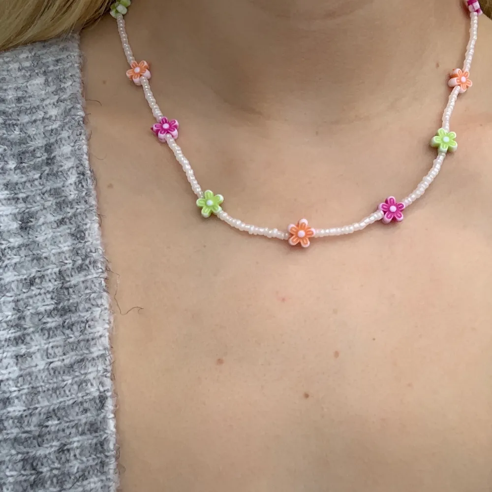 Vitt pärlhalsband med små pärlor och söta blommor i olika färger 🤍💞🦋💚💜 halsbandet försluts med lås och tråden är elastisk . Accessoarer.