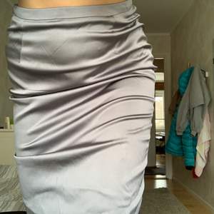 Grå satinliknande kjol med underkjol. Material: 75% viskos 22% polyamid 3% elastan Skick: bra skick knappt använd. Buda från 50kr
