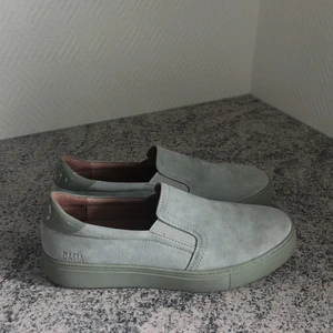 Dasia slip on - pastell gröna - Ett par slip on från märket Dasia i fin grön pastell  färg. Använt ett fåtal gånger men dom är nästan i nyskick. Påse medföljer. Strl. 41. Köparen står för frakten. 