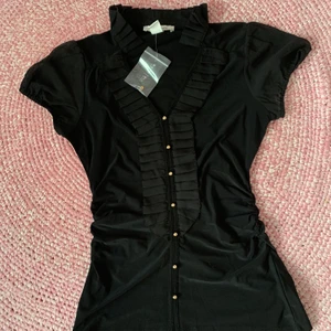 Blus från White House Black Market  - En svart stretchig blus med krås fram. Figurformad modell. Blusen har rynkad söm i sidorna. Från White House Black Market. Storlek XS. Aldrig använd 