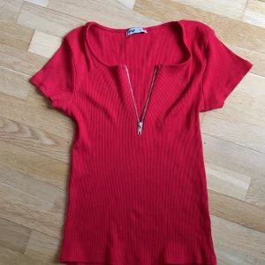 Röd T-shirt  - Det är en röd T-shirt med dragkedja. Har inte haft användning för den. Nypris 200kr 