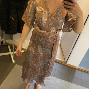 Klänning - Rosa mönstrad klänning med fint spänne i midjan, oanvänd 