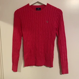 Rosa Kabelstickad Gant  - Rosa kabelstickad gant tröja, använd fåtal gånger men är i nyskick. Svårt att få korrekta färgen på bild, den är mer cerice i verkligheten och har en något varmare färg än på bilden