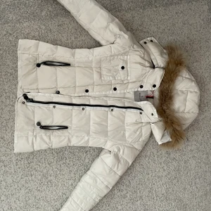 Vit Moncler Jacka - Säljer min fina moncler jacka. Jackan är i väldigt bra skick dock med ett hål vid ärmhålan (se bild 3) men det ska inte vara något stort besvär. Jackan är äkta (qr kod samt serielapp)  Pris kan diskuteras. Köp direkt för 1600. För fler bilder skriv. 