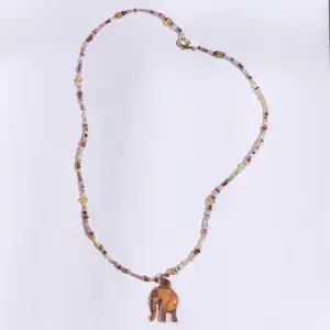 Ett guldigt pärlhalsband med elefant hänge. 