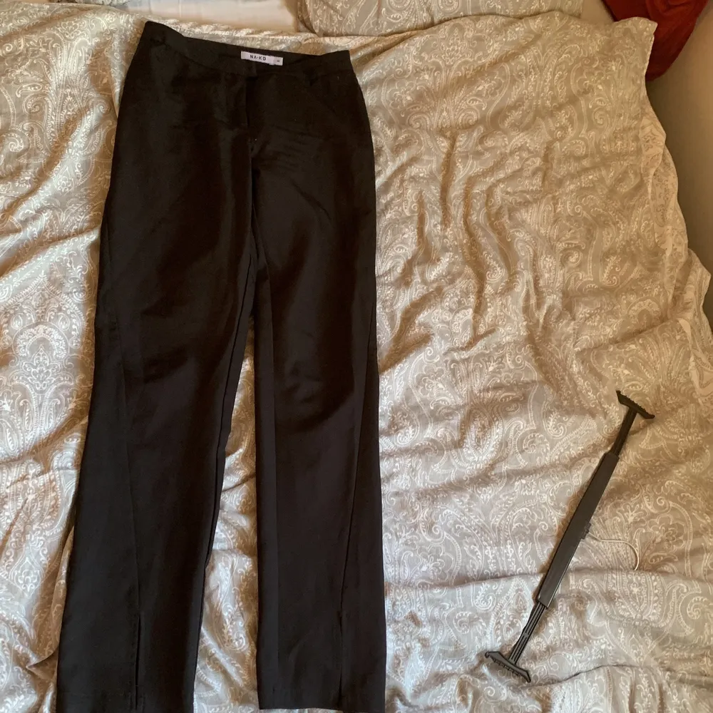 Svarta kostymbyxor från NAKD. Midwaisted, fake-kostymfickor där bak. Slits längst ner som går på framsidan av benet. Dem är i storlek 38.. Jeans & Byxor.