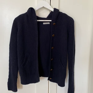 Marinblå stickad luvtröja - Säljer en marinblå stickad luvtröja med knappar från hunkydory. Pris: 155kr + frakt