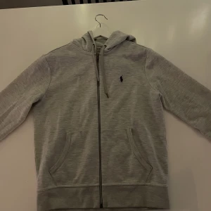 Grå Ralph Lauren zip hoddie - Säljer min ljusgråa zip hoddie från  Ralph Lauren i storlek S, pga får ingen användning av den längre. 