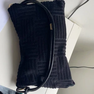 Svart väska  - Svart axelväska med fint mönster, axelbandet går att justera längd på och knyta hur man vill! Man får plats med mycket i den! 75kr💓