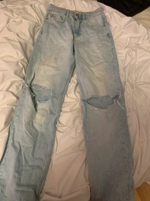 Jeans  -  ljus blåa jeans med hål på knäna. Sitter som mid Waist. Från Gina Tricot åt. 