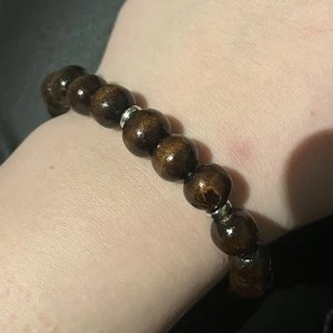 Axel armband  - Elastiskt armband med träpälor och silvriga mellan läga pärlor  Storlekar & pris (inklusive frakt) XS, 13-14,9 cm (31kr) S, 15-16,9 cm (31kr) M, 17-18,9 cm (32kr) L, 19-21,9 cm (33kr)