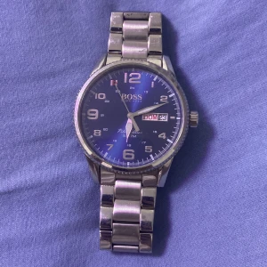 Hugo Boss klocka - Klockan tickar inte tror att det är batteriet och den har några skrapor men förutom det funkar den helt fint du kan ändra storlek på den också 