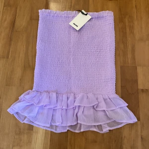Lila kjol - Lila smockad kjol från bikbok i storlek S. Helt oanvänd med prislapp kvar. Mini/midi längd beroende på hur lång man är. 