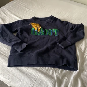 Gant  - Mörkblå gant tröja, med text i mitten som är grön, och en tiger uppe vid texten 