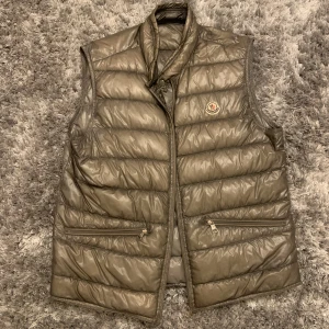 Moncler gui väst - Äkta moncler gui väst, köpt från HighEndMarkets (stor resell sida) för 3000kr. Nypriset på dessa västar ligger på 6000kr. Jag har orderbekräftelse på mail och kan skicka vid behov.  Storlek: 3 (motsvarar S/M) Skick: Västen är ihopsydd på bakre sidan.