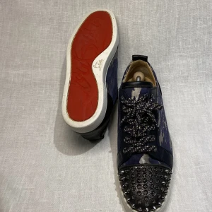 Christian Louboutin  - Christian Louboutin | Studded Plain Leather Sneakers   -Går ej att köpa längre  -Sällsynt färg -Svart/camo -Alla nitar kvar -Kondition: 7/10 -Storlek: 43  -Retail pris 8549 SEK -Pris 4500 SEK  Tveka inte på att kontakta oss, 