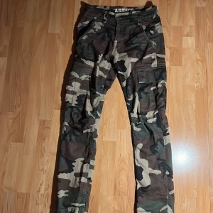 Alpha Industries Cargobyxor 30 - Utmärkt skick. Alpha Industries Cargobyxor robust material, woodland camo,  storlek 30 (Passar som S)
