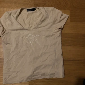 Topp med pärlbroderi - Beige topp med pärlbroderi och v-ringning. Vanlig längd- inte magtröja.