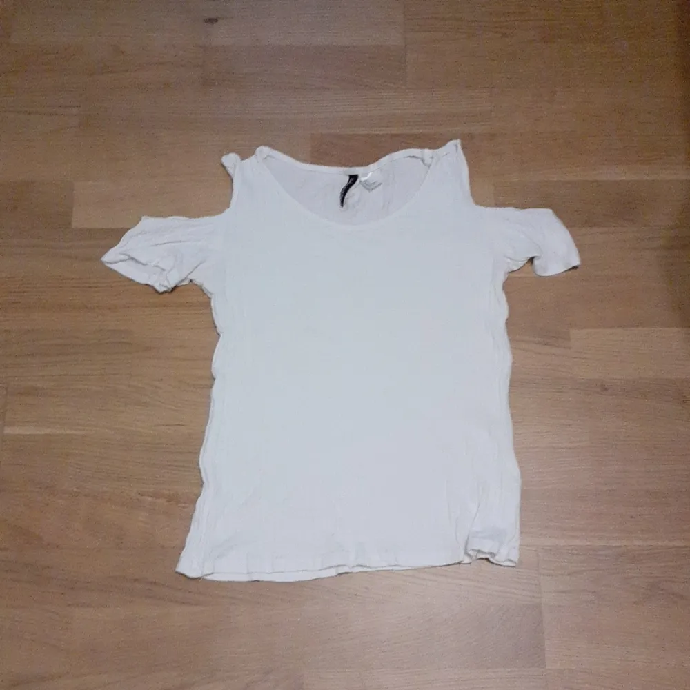 En fin vit t-shirt med ihåliga axlar som passar in i sommarn som kommer om ett tag. Har ingen användning av den så därför säljer jag :). T-shirts.