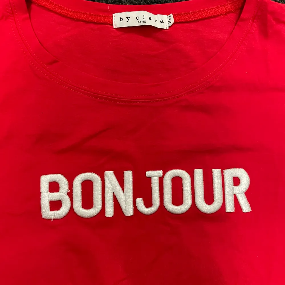 Röd t-shirt med texten ”Bonjour”. Knappt använd och i storlek S. Perfekt till vita jeans och någon härlig röd detalj. Även fint till blå eller svarta jeans. Färg är ju bara för underbart!!. T-shirts.