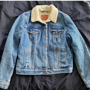 Mysig klassisker! Levis jacka med ludd - Klassiker!Ny skick,bara använts ett par gånger.Varm och go nu till hösten. Damstorlek: L men är liten i storleken, jag har annars storlek S-M o den passar jätte bra, helt beroende på hur man vill ha den, men passar även en L(nypris: 1499kr)