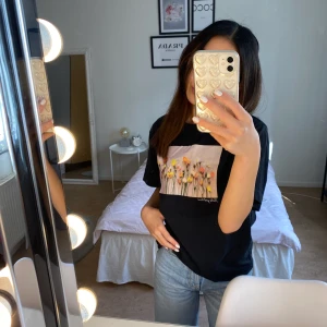 T-shirt med tryck från Monki - Svart t-shirt med tryck på från Monki. Kan mötas upp eller frakta.