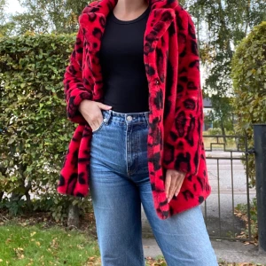 Röd kappa - Som man kan se på bild 2 har jag två likadana men olika storlekar, säljer den oanvända i storlek XS (kvar i påsen den kom i).  Röd kappa i leopardmönster, väldigt mjuk och går att stänga med knappar. Från NA-KD, orginalpris: 1099 kr.