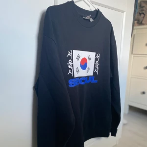 Oversized sweatshirt med ”Seoul”-tryck - En oversized sweatshirt i nyskick med ”Seoul”-tryck på framsidan. Den här tröjan sitter lite stor på mig.  Frakten är inräknad i priset och priset kan diskuteras vid snabb affär.