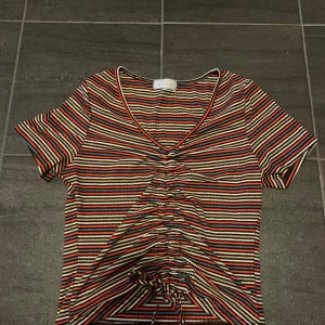 Randig tröja  - Färgglad tröja med snörning fram så man kan välja längden. Storlek står inte men skulle nog passa både medium och large då den är stretchig. Använd skick, köparen står för frakt. 