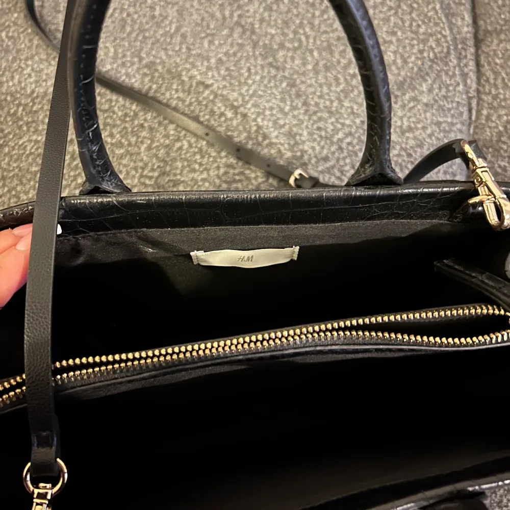 Fin och rymlig svart väska från hm i croc mönster, väskan har både handtag samt axelrem. Den har även fack inuti. Väskan har knappt använts och har ej skador/defekter. . Väskor.