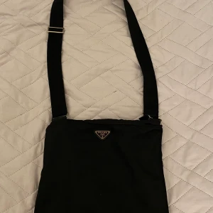 Prada crossbosybag - Dax att sälja min Prada väska. Den är köpt från Grailed. Bra skick förutom att loggan är lite repig och det är litet väldigt litet hål. Finns inte så mycket mer att säga så hör av dig vid funderingar