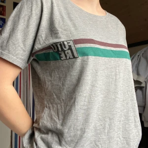 Grå T-Shirt - Grå T-shirt med trycket ”future”. Storlek S. 