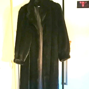 Black Faux Fur Size 38 - Längd 132 cm (krage till fåll). Knäpps med 5 hyskor. Made in England. Mkt elegant o använd 3 ggr för jag trodde jag skulle bli längre men jag krympte. Den söker därför nytt hem. Inköpspris £160 ny.