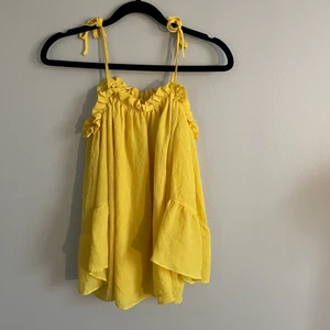 Gul partytopp med bara axlar - Gul partytopp i storlek medium det är knyt vid axlarna som gör att man kan låta ärmarna hänga ner, så det blir bara axlar. Fint skick, använd 1 gång.