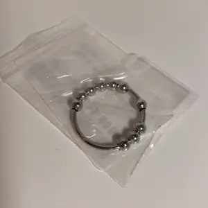 En fidget ring i silver som endast är testad. Anledning till att jag säljer den är för att det var i fel storlek. Ringen längst ner till höger är de måttet det är på ringen.