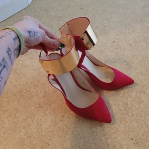 Röda stilett klackar  - Röda klackar med knäppe på baksidan. Klackhöjd: 10cm.