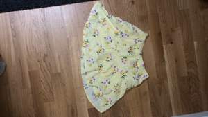 Kjolen har shorts under och den är väldigt lätt så den är bra för sommar dagar som är varma. Den är gul med rosa gröna och gula blommor. Den är aldrig använd och i storlek elva till tolv. 