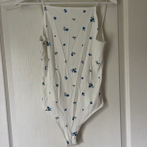 Vit body med blåa blommor  - Super fin vit body med blå blommor med en så fin djup rygg 